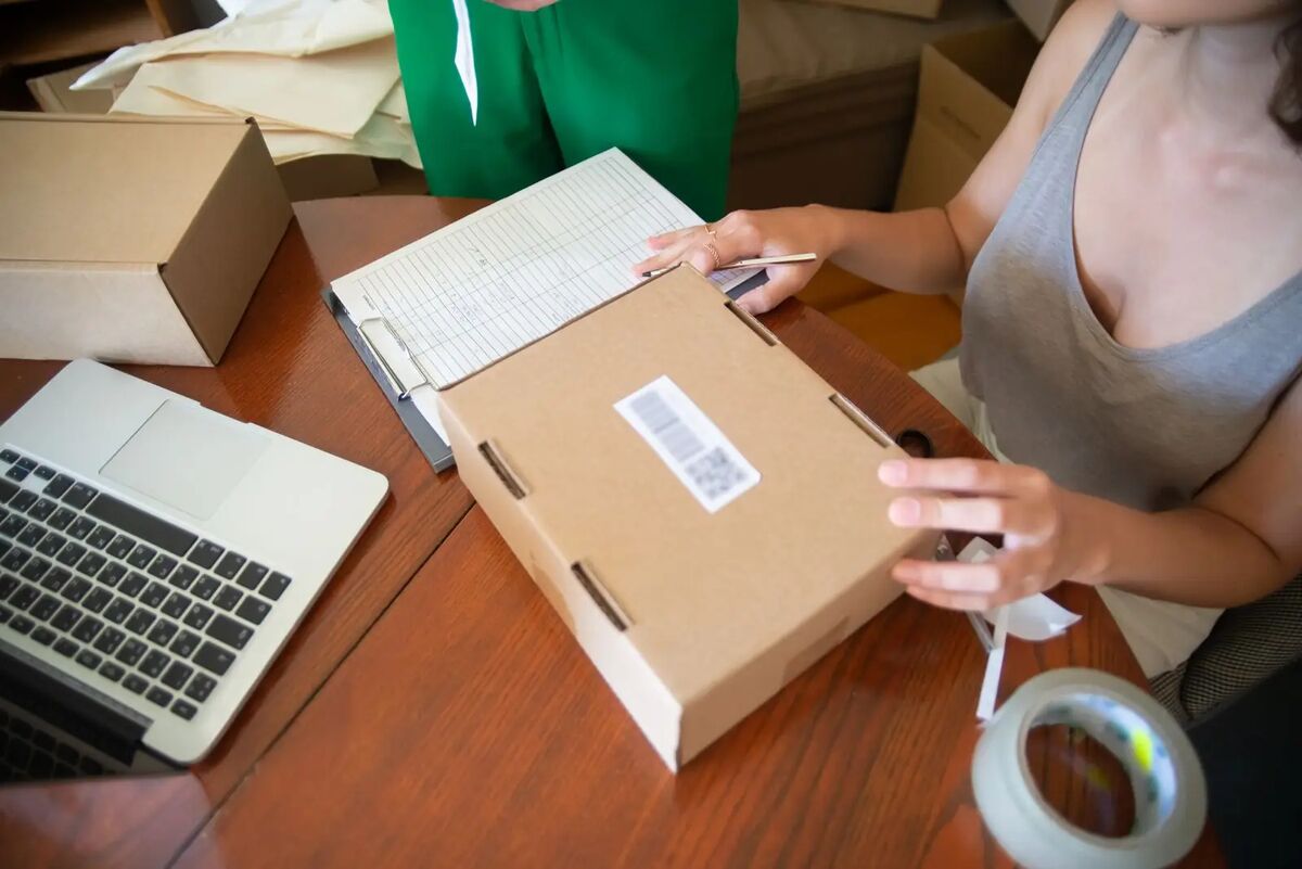 Stock photo: a seller packing an online order into a box, one part of a marketplace order
